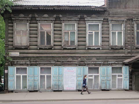 Woman passing by typical wooden house in Irkutsk